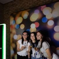 Three grads smile at photo booth holding champagne flutes